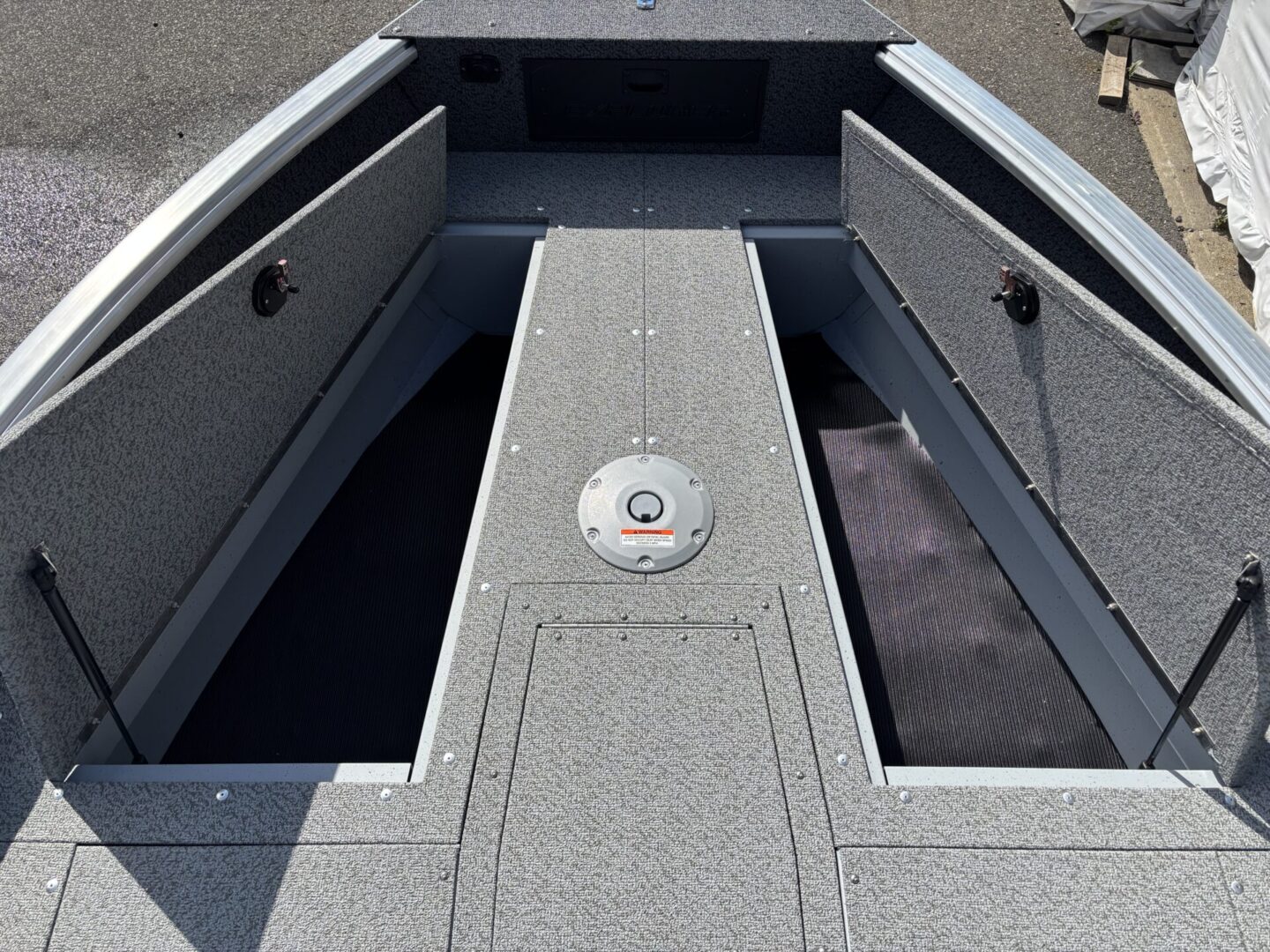 Open storage compartments on a boat deck with textured flooring.