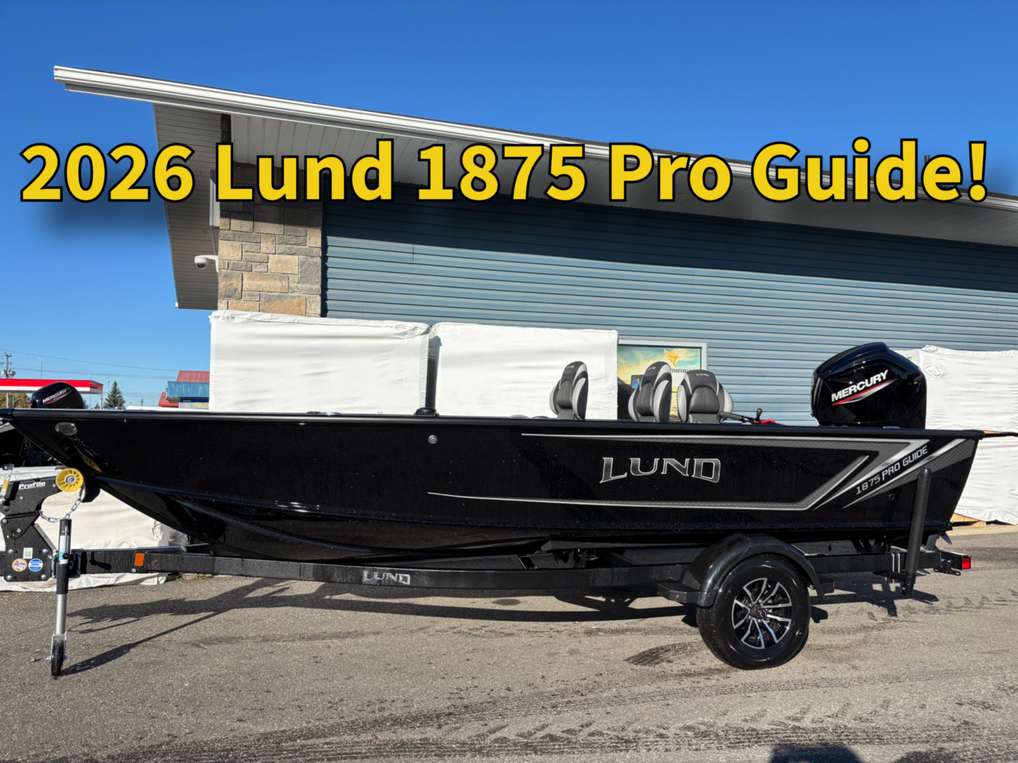 Black Lund 1875 Pro Guide fishing boat on trailer under clear blue sky.