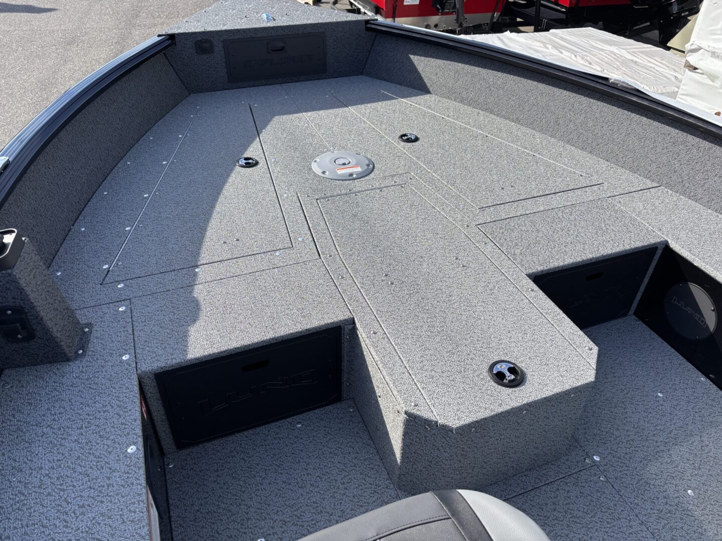Empty fishing boat deck with storage compartments and carpeted surface.