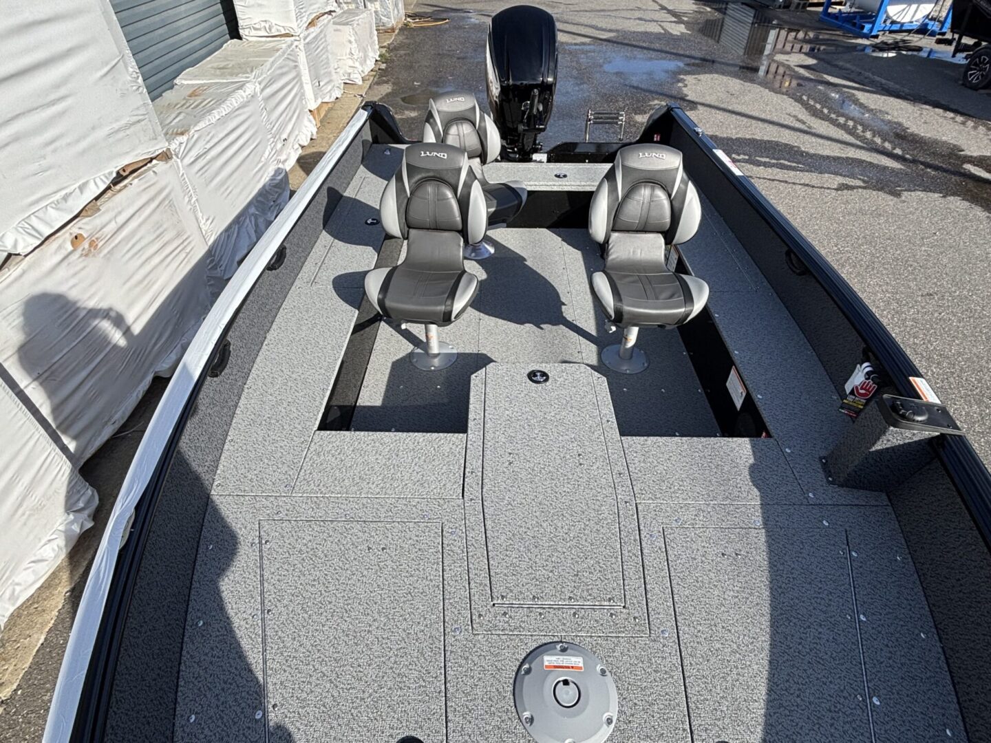 Fishing boat deck with four cushioned swivel seats and carpeted flooring.