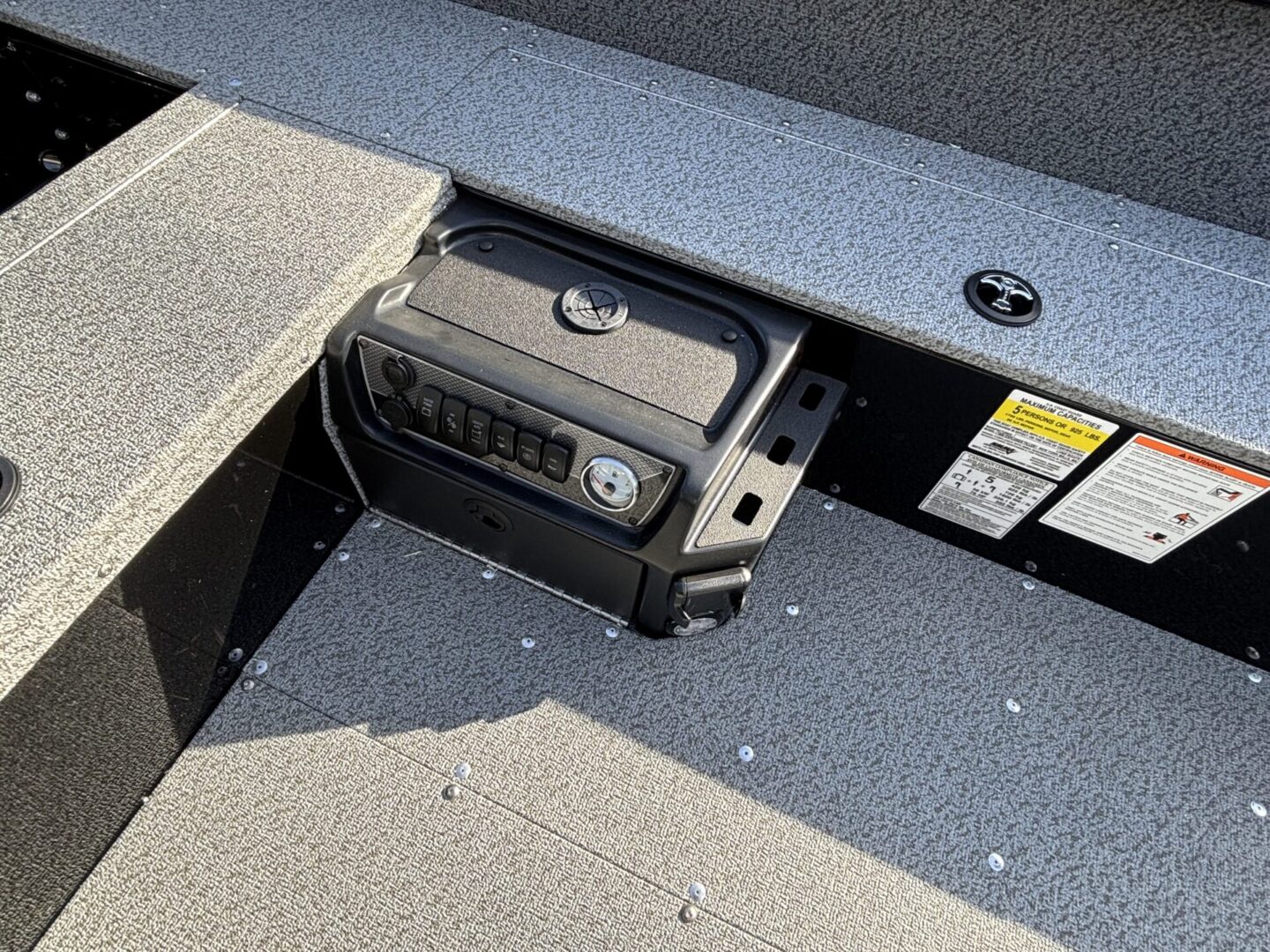 Boat battery secured in a compartment with safety labels nearby.