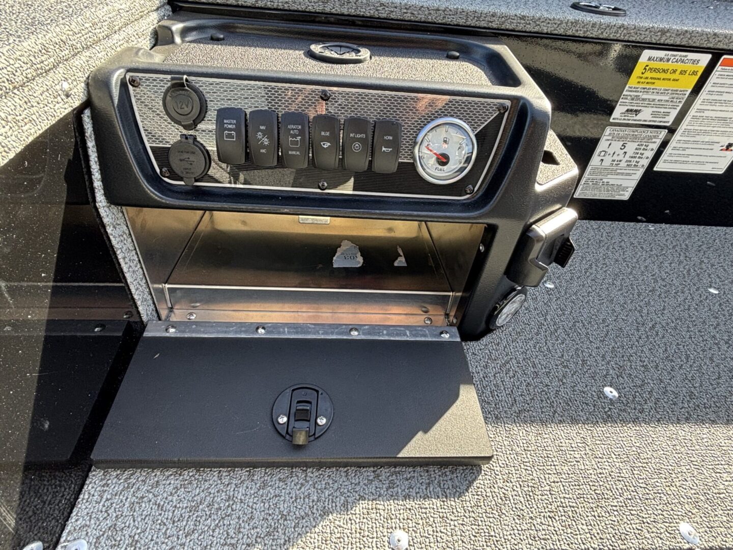 Control panel with switches and a pressure gauge on a metallic machine.