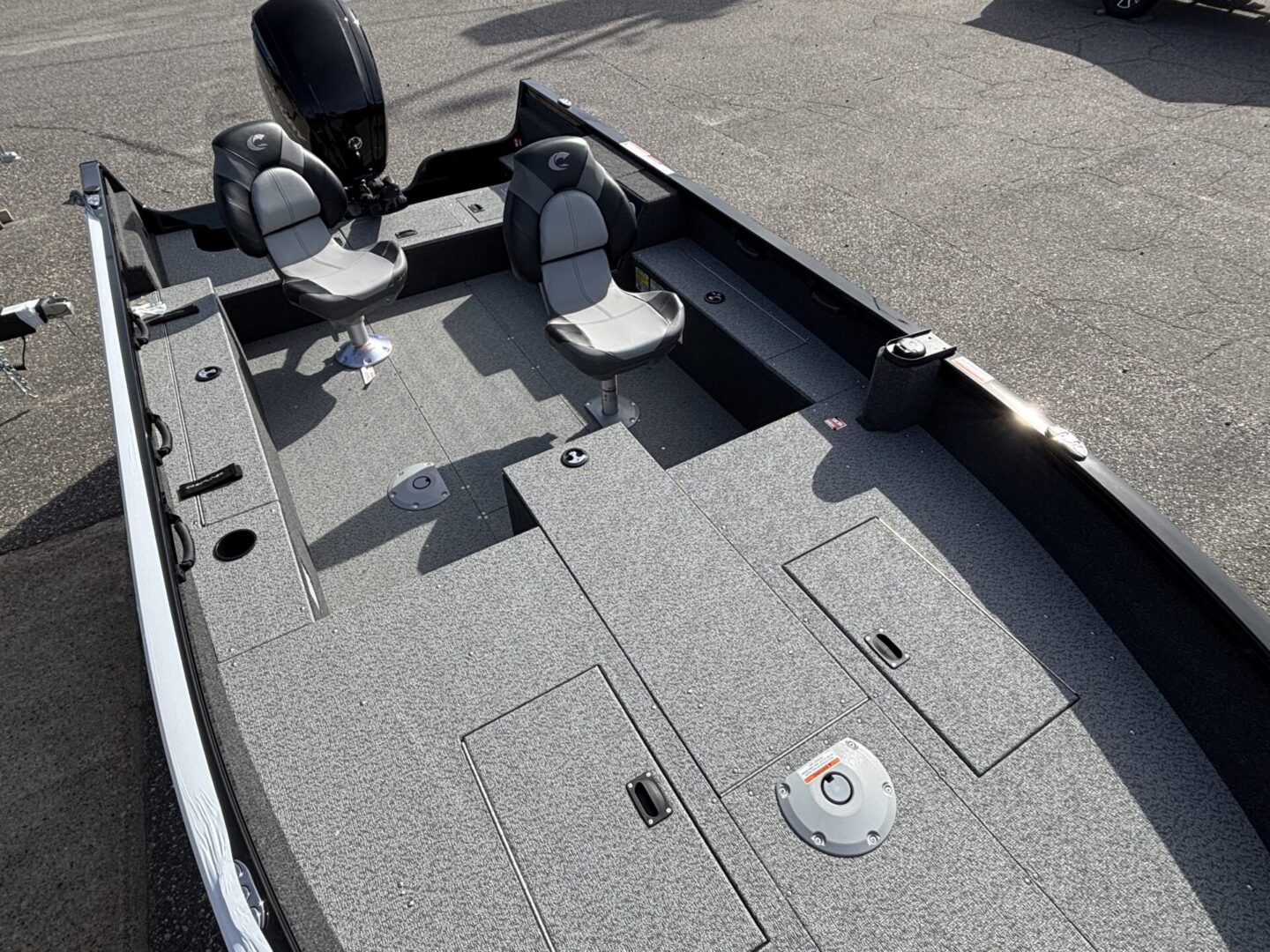Deck of a fishing boat with compartments and seats under bright sunlight.