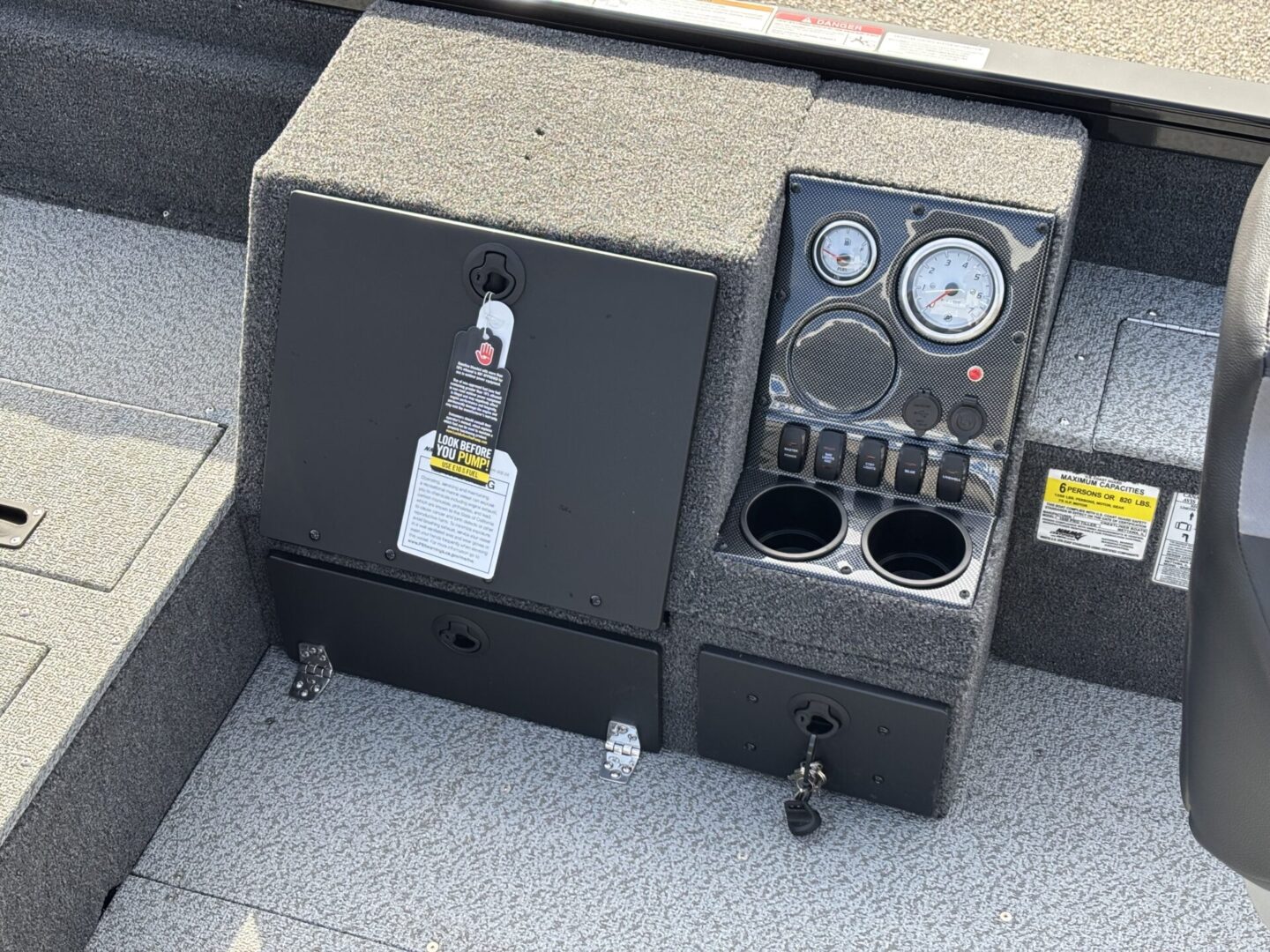 Boat control panel with gauges and switches beside a storage compartment.