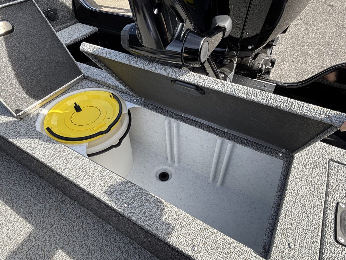 Open sink compartment on a boat with a yellow lided container beside it.
