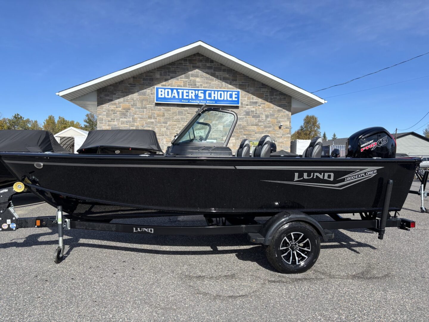 Black Lund boat on trailer parked outside a marine store.