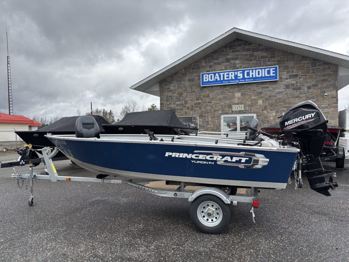 A blue and white fishing boat on a trailer in front of a brick building.