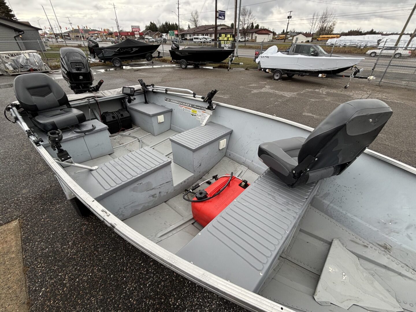 Small gray fishing boat with seating and a red fuel tank.