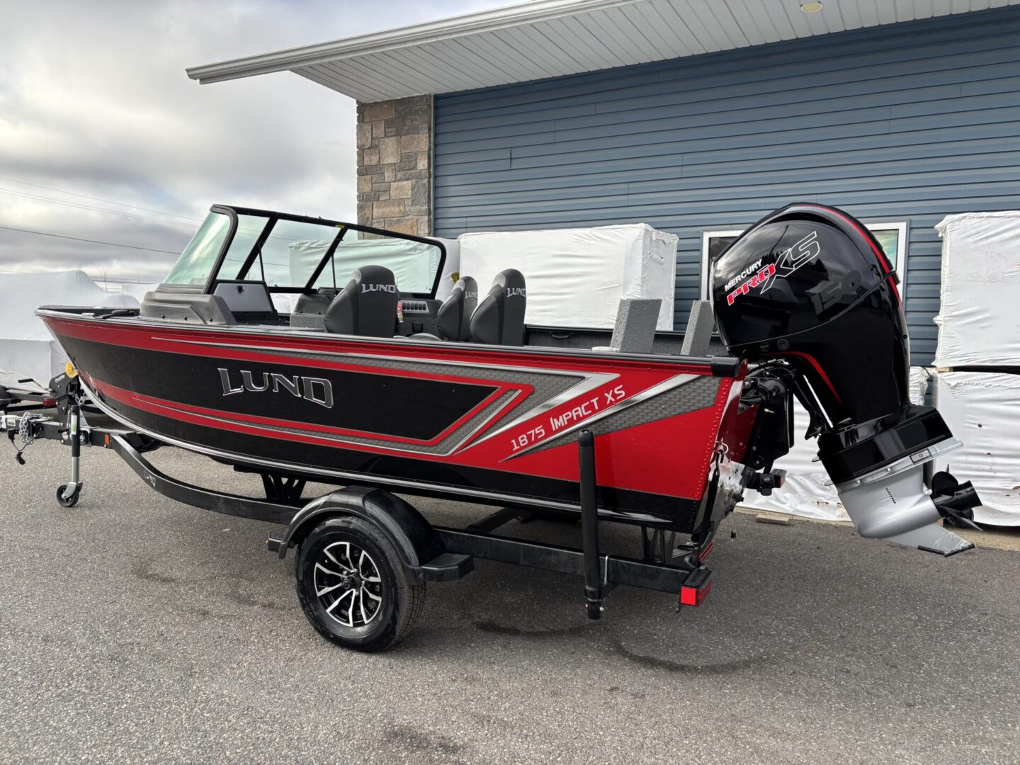 Red and black Lund fishing boat on a trailer with an outboard motor.