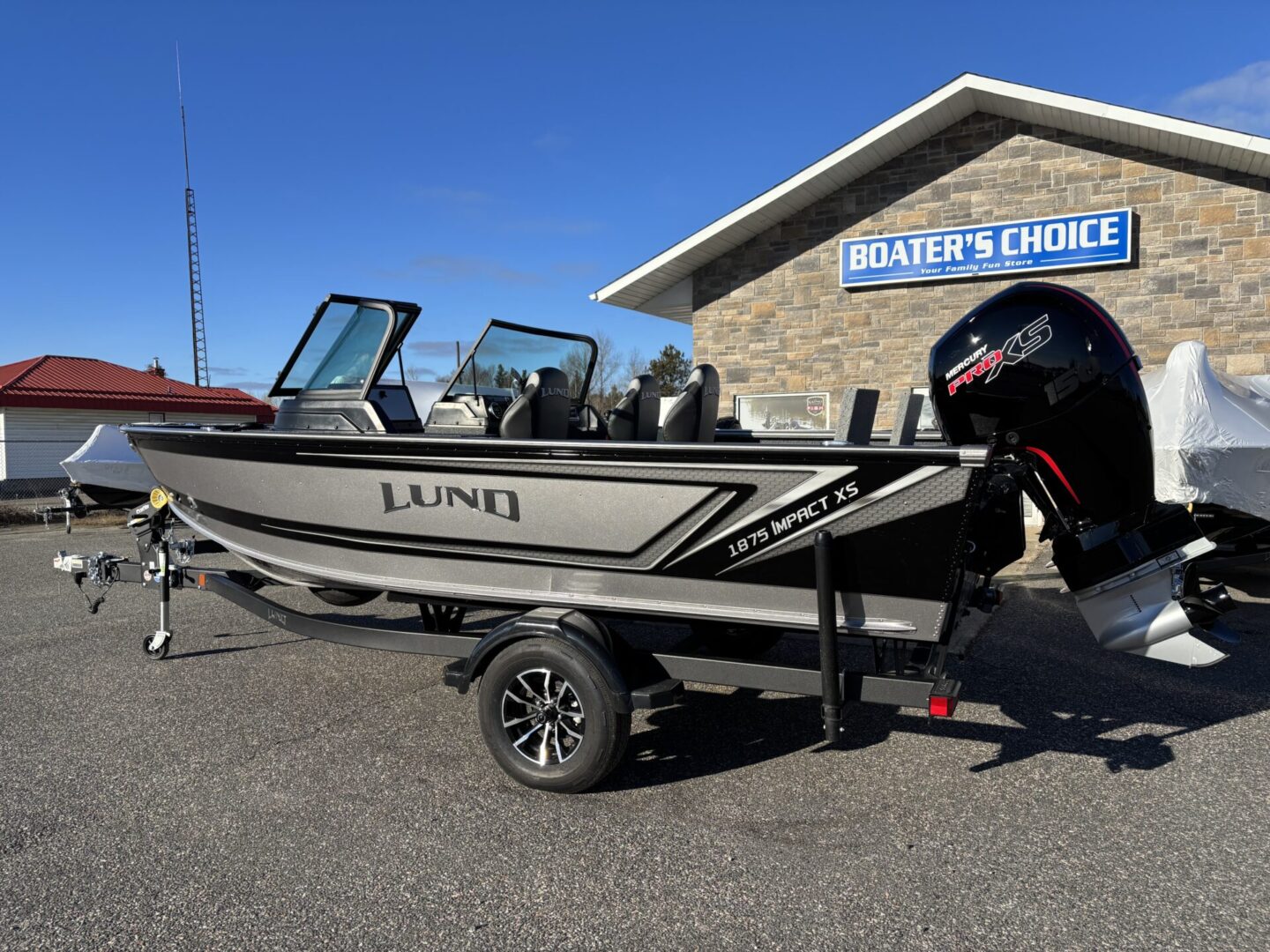 A sleek Lund fishing boat on a trailer outside a marine store.