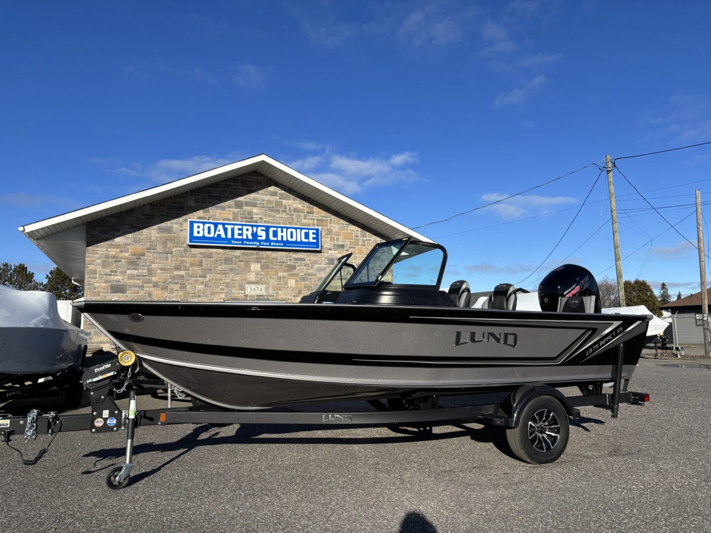 A black and gray fishing boat on a trailer outside a building.