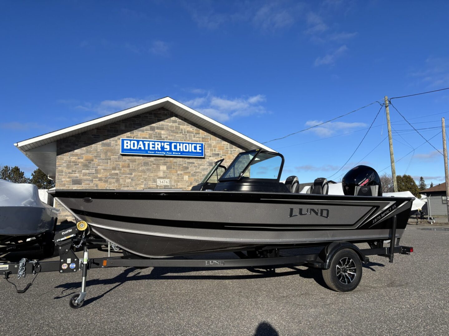 Black and silver fishing boat on trailer outside a mariner's office.
