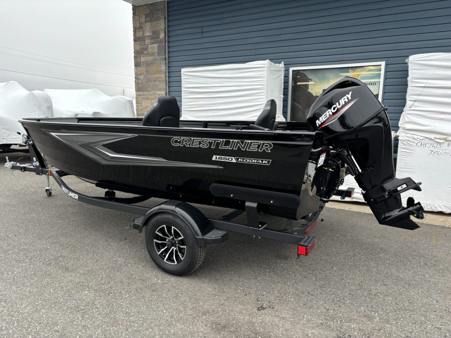 Black fishing boat on a trailer outside a building.