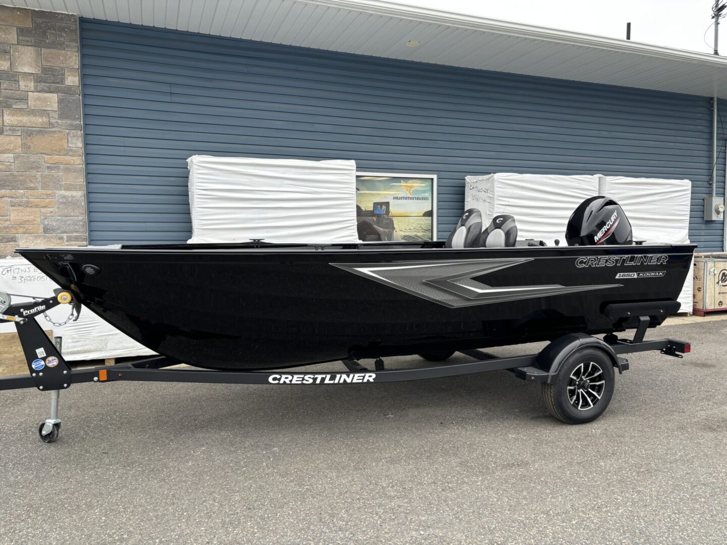 A sleek black Crestliner boat on a trailer parked outside.