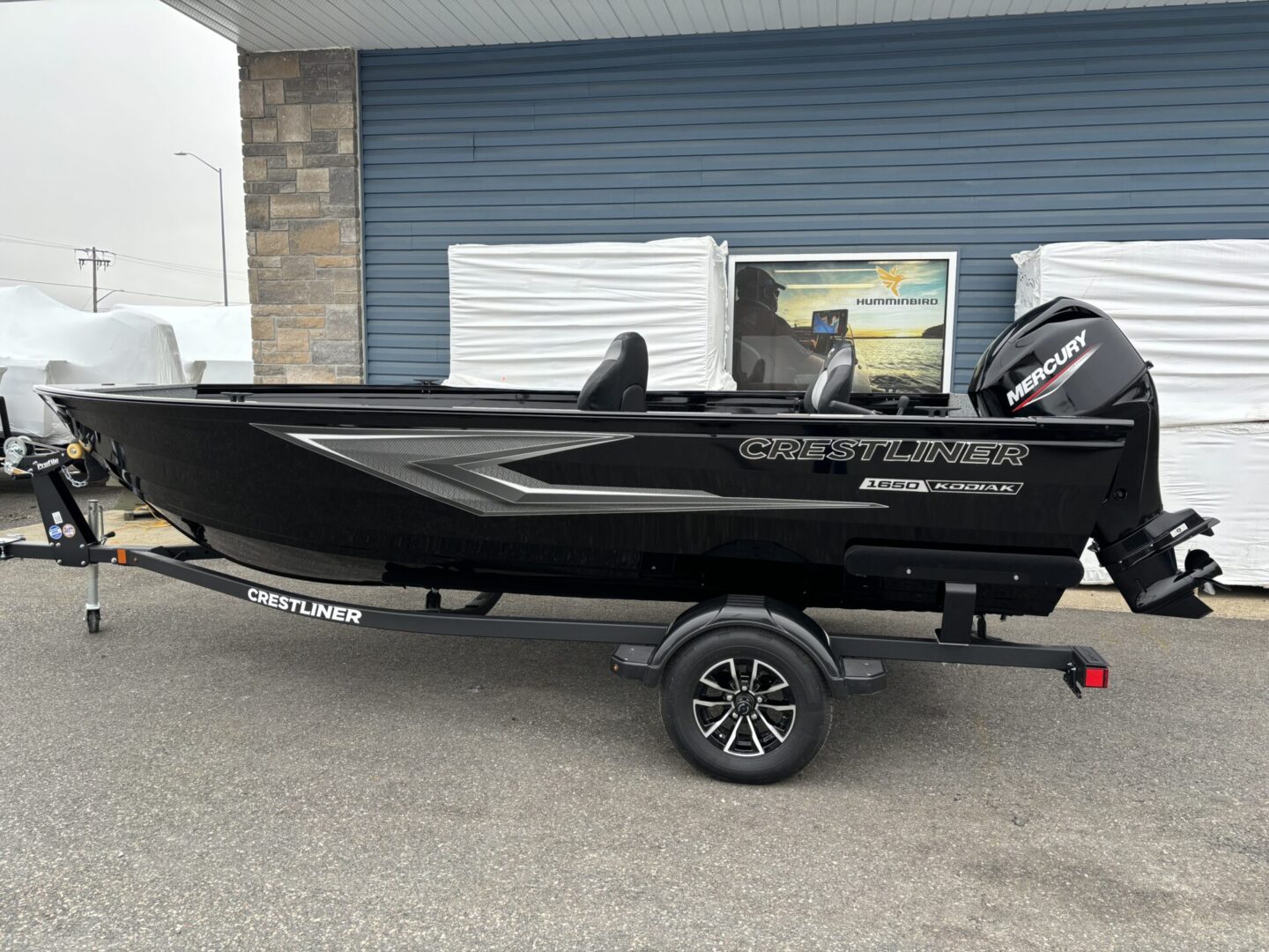 Sleek black motorboat on a trailer parked outside a building.