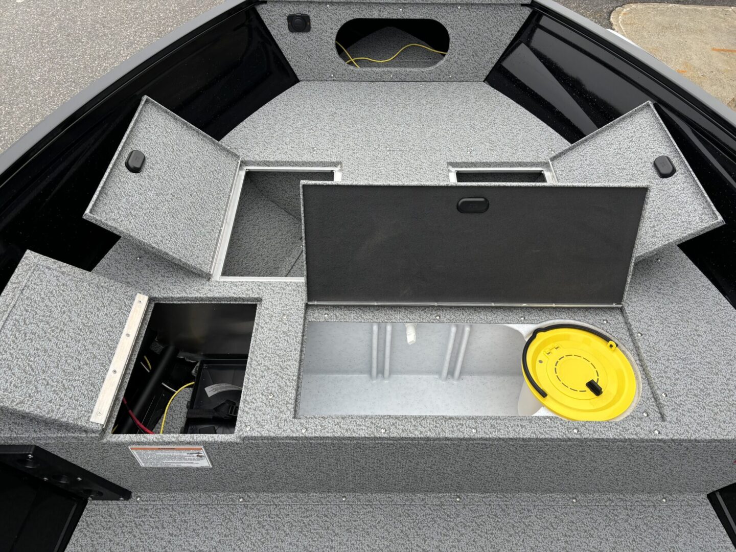 Open storage compartments in a boat or vehicle with various equipment inside.