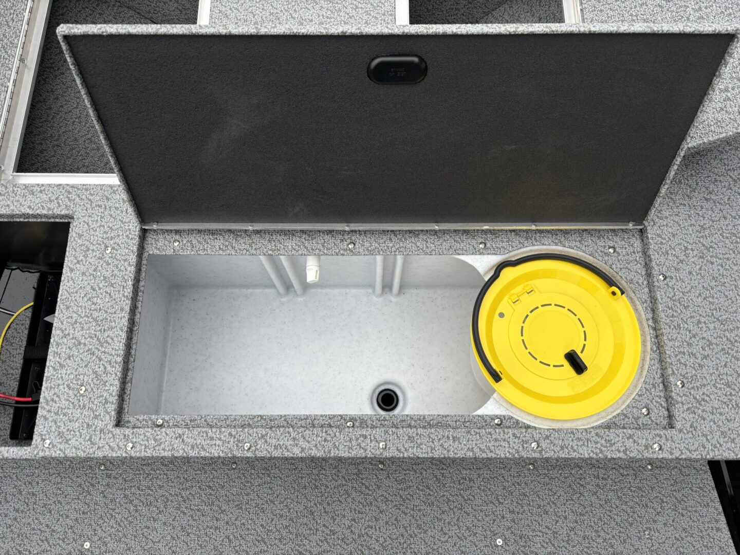 Open concrete utility box with a yellow lid container inside.