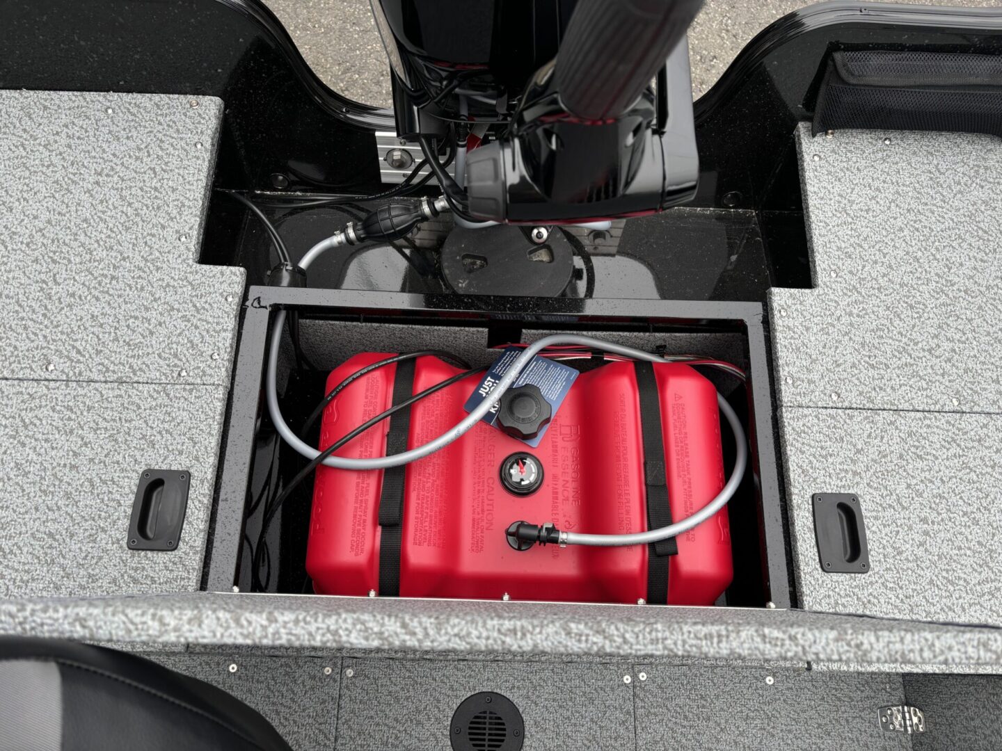 Red marine fuel tank installed in a boat's storage compartment.