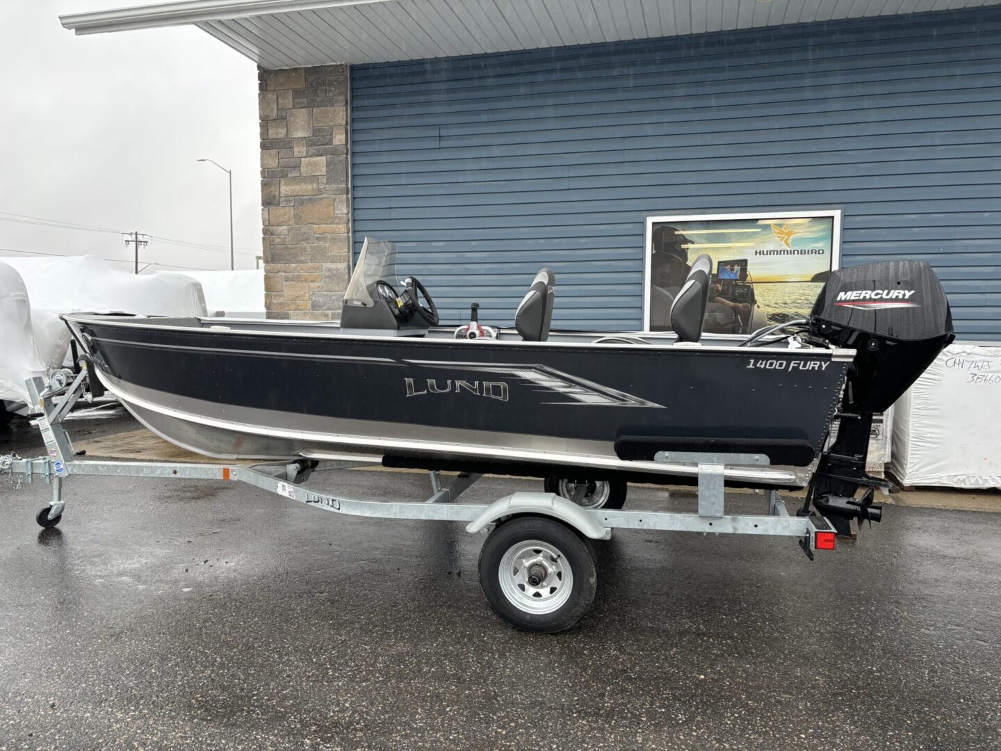 A sleek black motorboat on a trailer in front of a blue garage door.